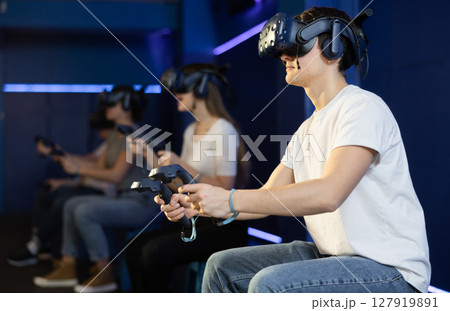 Guy with handheld controllers and VR glasses playing virtual game Guy with handheld controllers and VR glasses playing virtual game 127919891