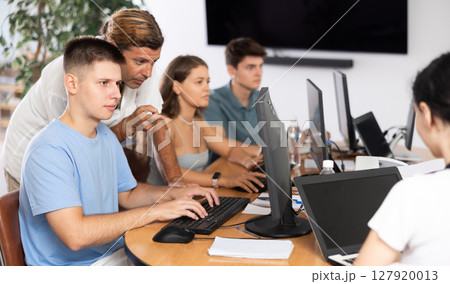 Male instructor assisting motivated guy during computer course 127920013