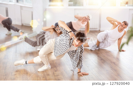 Concetrated guys and girls studying movement of contemporary dance in classroom with his friends 127920040