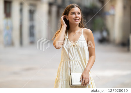 Young woman looks around on city street 127920050