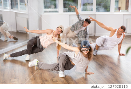 Girl and her students perform hip hop dance on one bent leg, movement in horizontal plane near floor 127920116