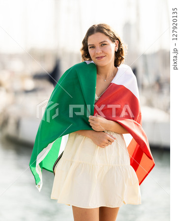 Young woman wrapped in Italian flag in port 127920135