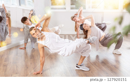 Man and his students perform hip hop dance on one bent leg, movement in horizontal plane near floor 127920151