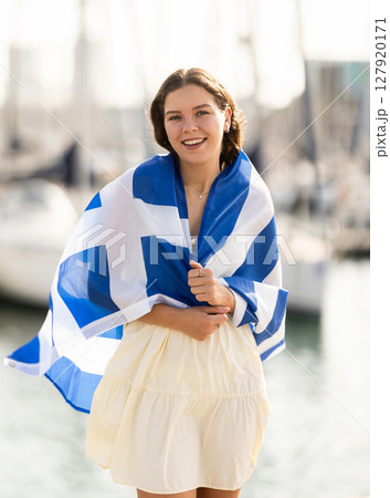 Young woman wrapped in Greek flag at port 127920171