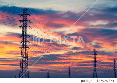 夕焼けに染まる空と立ち並ぶ送電鉄塔　暖色寒色強調 127920174