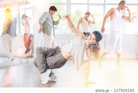 Group of energetic hip hop dancers focused on training while gathered together in spacious dance hall 127920185