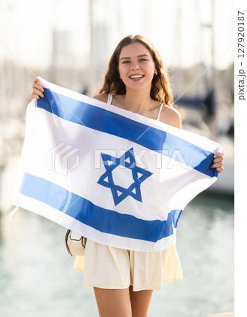 Woman waving national flag of Israel against seaport and yachts 127920187