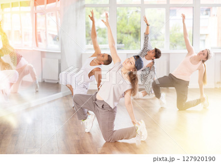 Girl and her students perform hip hop dance on one bent leg, movement in horizontal plane near floor 127920190