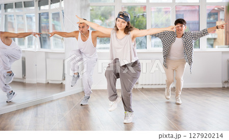 Young girl standing performs basic hip hop movements in front of group of students Young girl standing performs basic hip hop movements in front of group of students 127920214