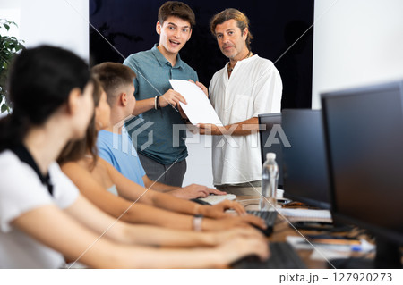 Tutor presenting certificate of completion of computer courses to satisfied guy 127920273