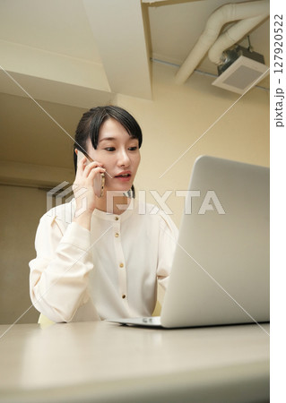 パソコン画面を見ながら電話をする女性 127920522