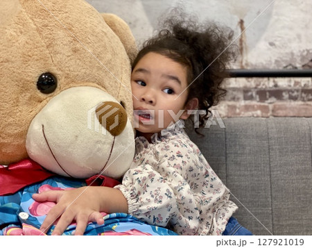 Cute little girl playing with a teddy bear on the sofa Cute little girl playing with a teddy bear on the sofa 127921019