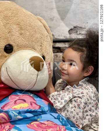 Little girl with a teddy bear in her arms, close up 127921166
