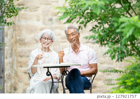 ベンチに座ってお茶を飲むシニア夫婦 127921757