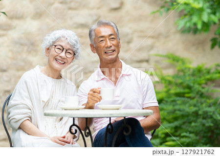 ベンチに座ってお茶を飲むシニア夫婦 127921762