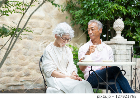庭でコーヒーを飲むシニア夫婦 127921768