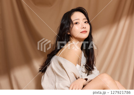 ベージュの布地背景で撮影をした若い女性の高級感のある美容ポートレート 127921786