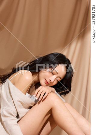 ベージュの布地背景で撮影をした若い女性の高級感のある美容ポートレート 127921788