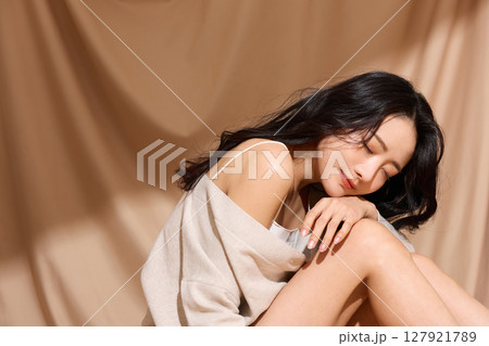 ベージュの布地背景で撮影をした若い女性の高級感のある美容ポートレート 127921789