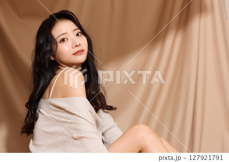 ベージュの布地背景で撮影をした若い女性の高級感のある美容ポートレート 127921791