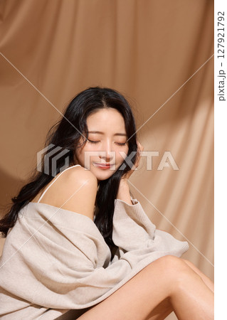 ベージュの布地背景で撮影をした若い女性の高級感のある美容ポートレート 127921792