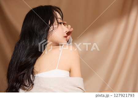 ベージュの布地背景で撮影をした若い女性の高級感のある美容ポートレート 127921793