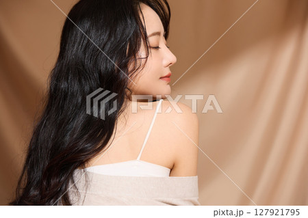 ベージュの布地背景で撮影をした若い女性の高級感のある美容ポートレート 127921795