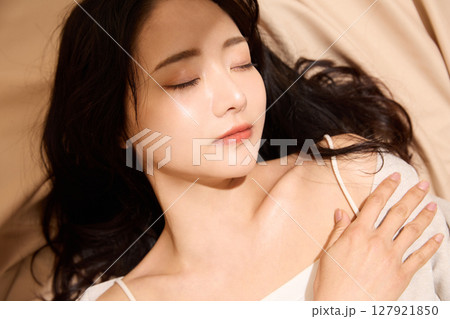ベージュの布地背景で撮影をした若い女性の高級感のある美容ポートレート 127921850