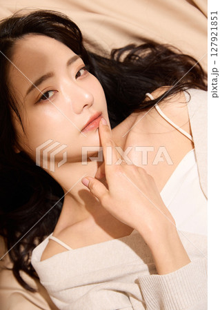 ベージュの布地背景で撮影をした若い女性の高級感のある美容ポートレート 127921851