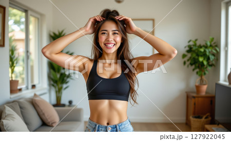 Young woman smiling in cozy living room, showcasing fitness and confidence 127922045