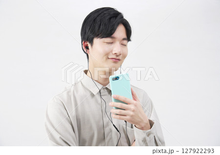 イヤホンをつけて音楽を聴く20代男性 白背景 イヤホンをつけて音楽を聴く20代男性 白背景 127922293