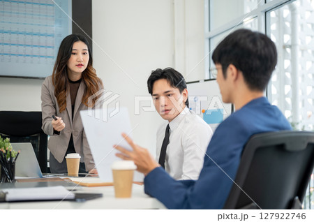 Businessman or male office worker holding a document and asking a question with his female coworker. Businessman or male office worker holding a document and asking a question with his female coworker. 127922746
