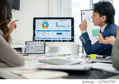 Businessman or male office worker talking about the financial report on monitor with his coworkers 127922767