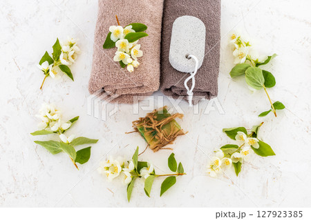Towels with body care products and branches of jasmine on the white background. 127923385
