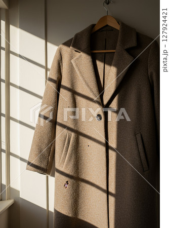 Moth eaten coat hanging in sunlight by window, damage and repair concept Moth eaten coat hanging in sunlight by window, damage and repair concept 127924421