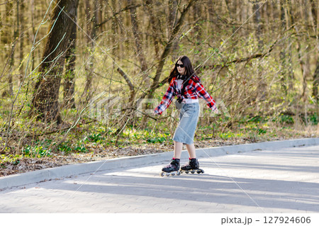 Young woman roller skating in a park during spring enjoying a sunny day 127924606