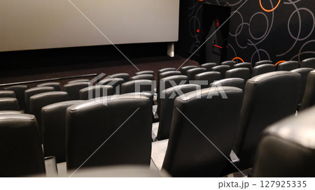 Rows of empty black leather cinema seats in a modern movie theater 127925335