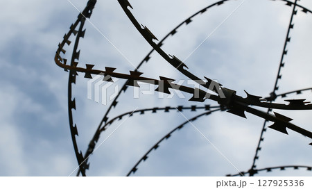Prison wall and barbed wire under blue sky Prison wall and barbed wire under blue sky 127925336