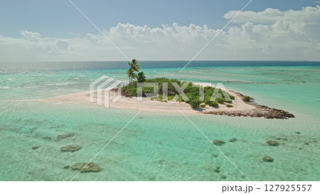A stunning aerial view captures a secluded tropical island surrounded by vibrant turquoise waters. The sandy shore complements the greenery, showcasing nature's beauty. A stunning aerial view captures a secluded tropical island surrounded by vibrant turquoise waters. The sandy shore complements the greenery, showcasing nature's beauty. 127925557