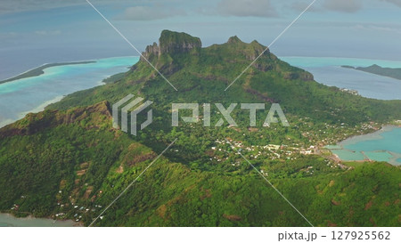 Lush vegetation covers almost entirely mount otemanu, the highest point of bora bora island, while turquoise waters lap against the sandy shores below Lush vegetation covers almost entirely mount otemanu, the highest point of bora bora island, while turquoise waters lap against the sandy shores below 127925562