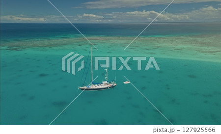 A large sailing vessel with multiple masts is anchored in crystal-clear turquoise waters. 127925566