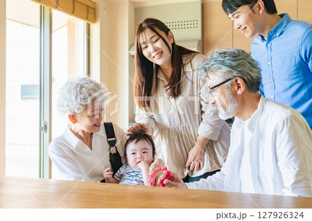 笑顔で赤ちゃんを囲む三世代家族 笑顔で赤ちゃんを囲む三世代家族 127926324
