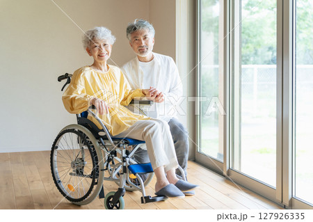 車椅子に乗ったシニア女性を介護するシニア男性 127926335