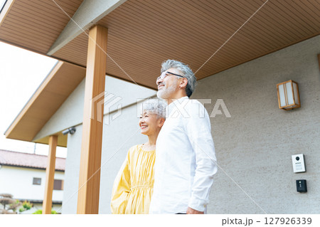 笑顔で住宅の前に立つシニアカップル 127926339