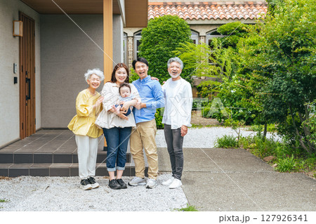 住宅の前で赤ちゃんを笑顔で囲む三世代家族の集合写真 127926341