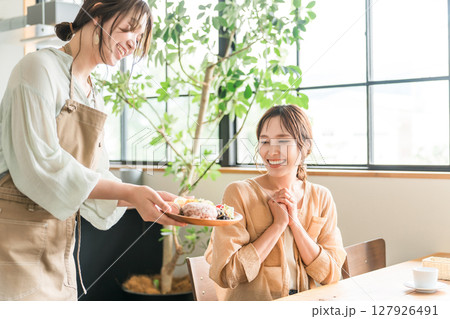 カフェでワンプレートランチを提供する店員と女性客 127926491