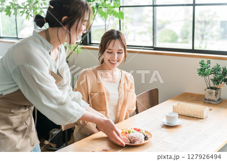 カフェでワンプレートランチを提供する店員と女性客 127926494