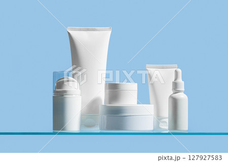 Various white cosmetic containers on blue glass shelf Various white cosmetic containers on blue glass shelf 127927583