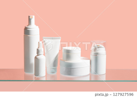 White cosmetic containers on glass shelf 127927596