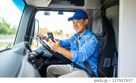 トラックの中でスマホを見て荷待ちの作業員 127927637